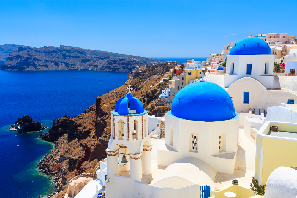 Santorini, Greece, panoramic white buildings against blue sea and sky.